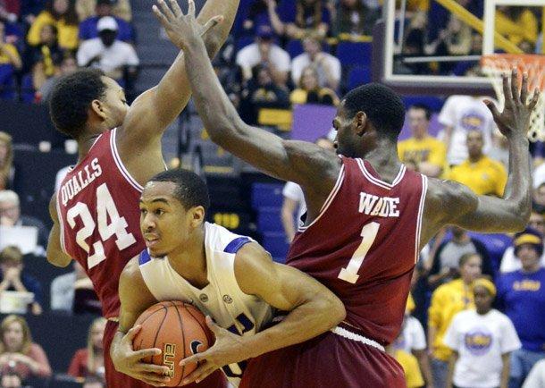 LSU's Charles Carmouche (00) is sandwiched between Arkansas' Michael Qualls (24) and Mardracus Wade (1) during their NCAA college basketball game, Wednesday, Feb. 27, 2013, in Baton Rouge, La. LSU won 65-60. (AP Photo/The Advocate, Heather McClelland)
 