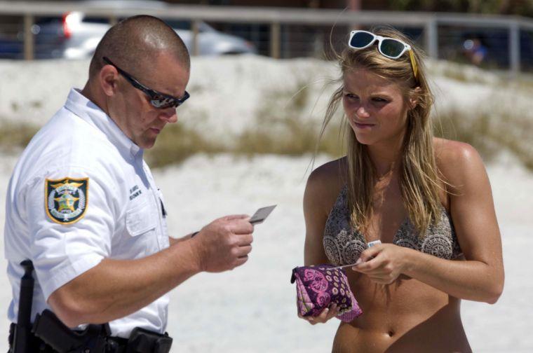 Walton County Deputy Sheriff Brad Barefield, left, checks the IDs of Jenna Harris and other spring breakers from Mississippi on the beach in South Walton County, Florida on Wednesday, March 13, 2013. As thousands of spring breakers descend on the beaches in this northwest Florida resort area, law enforcement personnel are making regular sweeps along the beaches looking for underage drinkers. Editor note: Jenna Harris and the others in her party were over 21 years old and not ticketed. (AP Photo/Northwest Florida Daily, Devon Ravine)
 