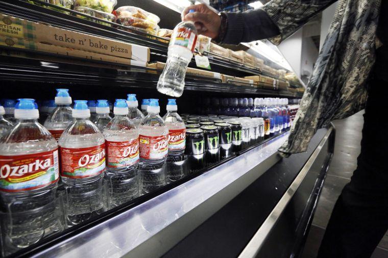 In this Tuesday, March 5, 2013 photo, a customer takes a bottle of water off a store shelf in Jackson, Miss. As sugary drinks come under fire for fueling obesity rates, people are increasingly reaching for bottled water as a healthier, relatively affordable alternative. Already, bottled water has surged past juice, milk and beer in terms of per capita consumption. The result is that bottled water is slowly closing the gap for the No. 1 spot. (AP Photo/Rogelio V. Solis)
 