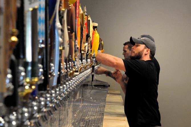 Co-owner of The Pelican House and LSU graduate, Cris Juge, works on one of the many beer taps at the new bar. The Pelican House, when completed, will boast the most draft beers on tap in the state at 136.
 