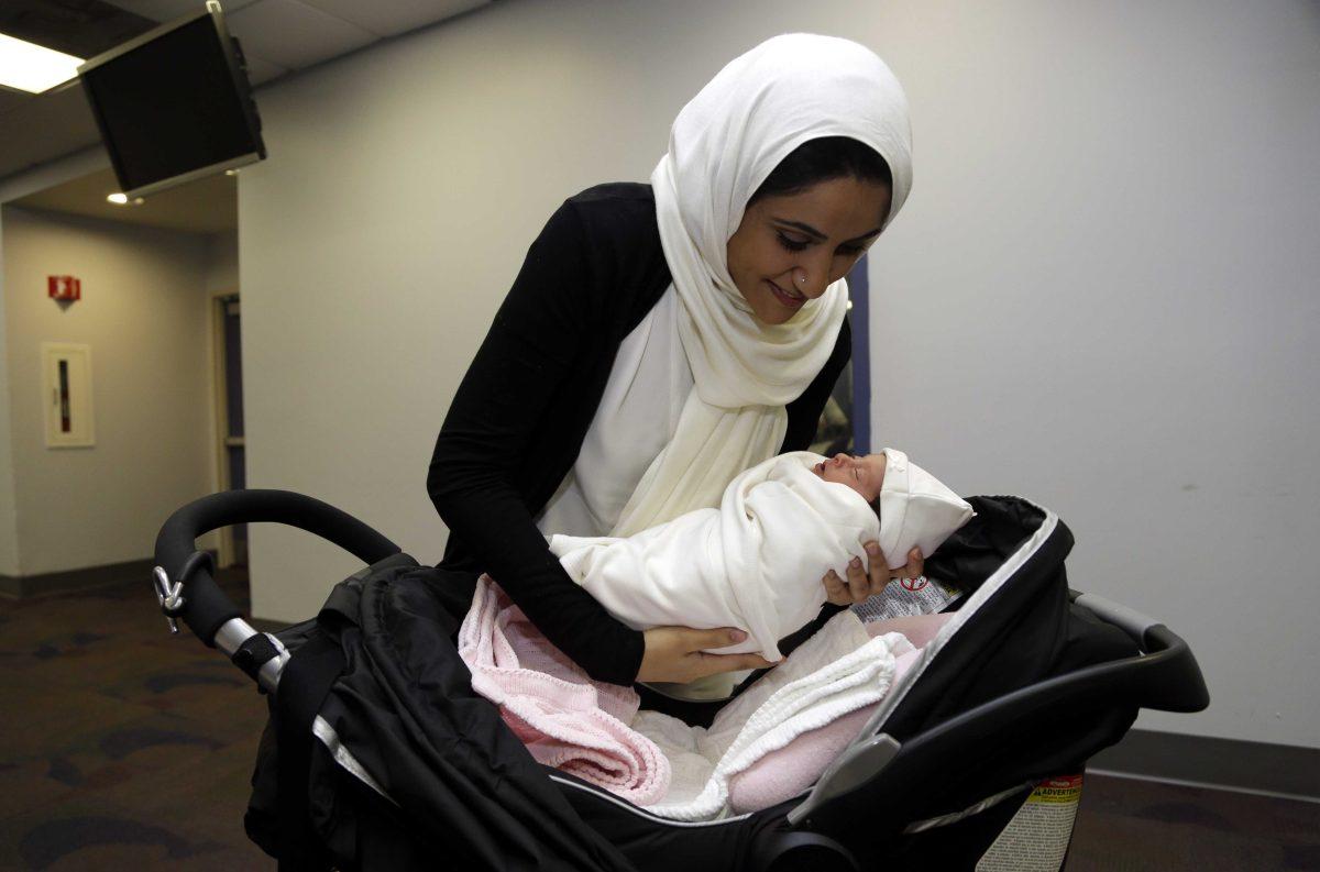 Fatema Al Ansari of Qatar, left, places her baby Alkadi Alhayal in a stroller following a news conference at Jackson Memorial Hospital, Wednesday, March 13, 2013, in Miami. Al Ansari was diagnosed with a condition called mesenteric thrombosis at age 19, causing her abdominal organs to fail. She is the first multivisceral transplant patient in the world to conceive and give birth. (AP Photo/Lynne Sladky)