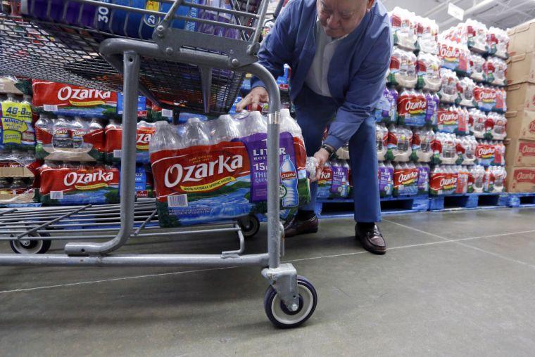 In this Tuesday, March 5, 2013 photo, Walter Pugh, 83, of Belzoni, Miss., loads a case of his bottled water into his shopping cart in Jackson, Miss. As sugary drinks come under fire for fueling obesity rates, people are increasingly reaching for bottled water as a healthier, relatively affordable alternative. Already, bottled water has surged past juice, milk and beer in terms of per capita consumption. The result is that bottled water is slowly closing the gap for the No. 1 spot. (AP Photo/Rogelio V. Solis)
 