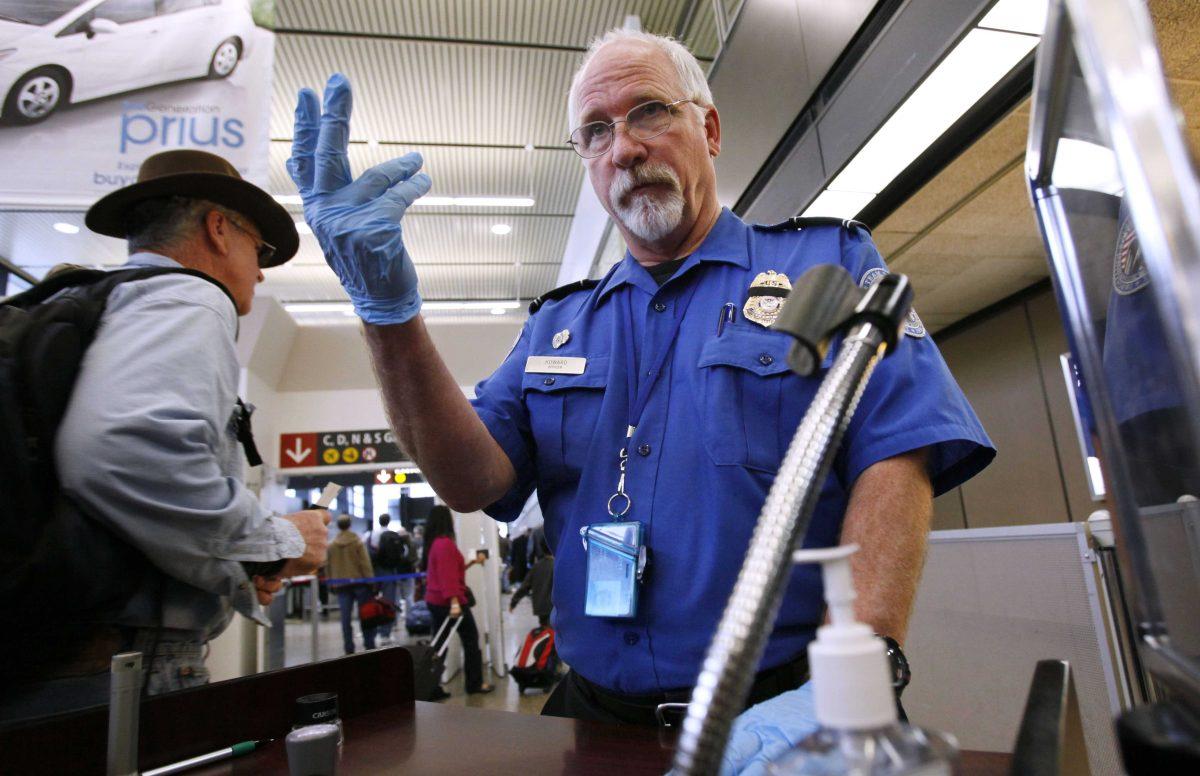 FILE - In this Jan. 4, 2010 file photo, TSA officer Robert Howard signals an airline passenger forward at a security check-point at Seattle-Tacoma International Airport in SeaTac, Wash. Flight attendants, pilots, federal air marshals and even insurance companies are part of a growing backlash to the Transportation Security Administration&#8217;s new policy allowing passengers to carry small knives and sports equipment like souvenir baseball bats and golf clubs onto planes. (AP Photo/Elaine Thompson, File)