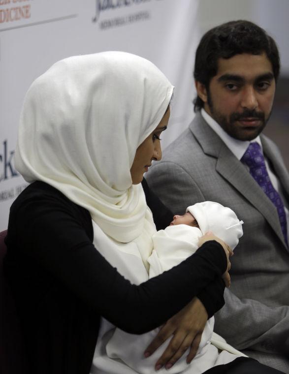 Fatema Al Ansari of Qatar, left, holds her baby Alkadi Alhayal, as her husband Khalifa Alhayal, right, looks on during a news conference at Jackson Memorial Hospital, Wednesday, March 13, 2013, in Miami. Al Ansari was diagnosed with a condition called mesenteric thrombosis at age 19, causing her abdominal organs to fail. She is the first multivisceral transplant patient in the world to conceive and give birth. (AP Photo/Lynne Sladky)
 