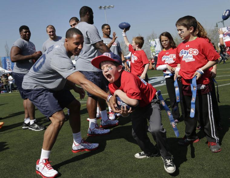 NFL draft prospect Eric Reid of LSU, left, hands of a ball to a kid during a youth football clinic in New York, Wednesday, April 24, 2013. Many of the top 2013 NFL draft picks are in town for the NFL draft. (AP Photo/Seth Wenig)
 