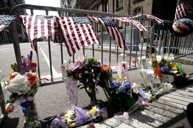 Flowers sit at a police barrier near the finish line of the Boston Marathon in Boston Tuesday, April 16, 2013. The bombs that ripped through the crowd at the Boston Marathon, killing at least three people and wounding more than 170, were fashioned out of pressure cookers and packed with shards of metal, nails and ball bearings to inflict maximum carnage, a person briefed on the investigation said Tuesday. (AP Photo/Winslow Townson)
 