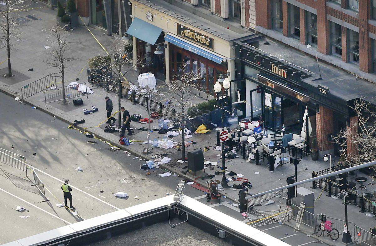 One of the blast sites on Boylston Street near the finish line of the 2013 Boston Marathon is investigated and guarded by police in the wake of two blasts in Boston Monday, April 15, 2013. (AP Photo/Elise Amendola)