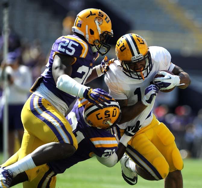 LSU junior running back Terrence Magee (14) braces himself against a tackle from purple squad junior defensive back Tre' Sullivan (21) Saturday, April 20, 2013 in the National L Club Spring Game in Tiger Stadium.
 