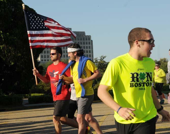 A man runs with an American flag Saturday, April 20, 2013, during the Baton Rouge Run for Boston, a 2.62 mile run organized by several local running clubs to support victims of the Boston Marathon bombing.
 