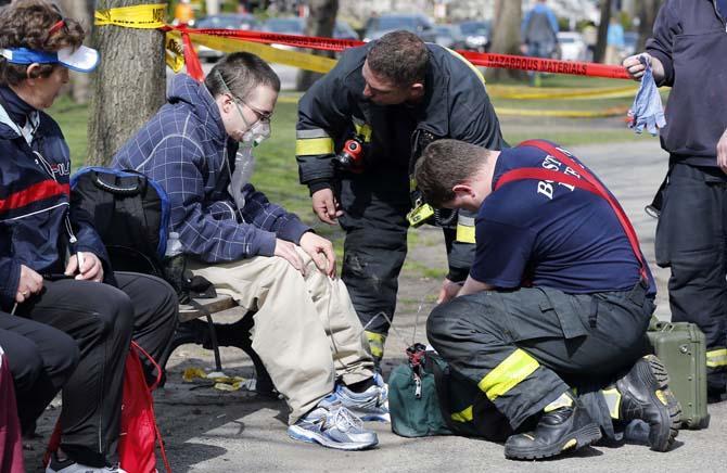 Firefighters tend to a man following an explosion at the finish line of the Boston Marathon in Boston, Monday, April 15, 2013. Two bombs exploded at the Boston Marathon finish line Monday killing at least two people injuring dozens. (AP Photo/Michael Dwyer)
 