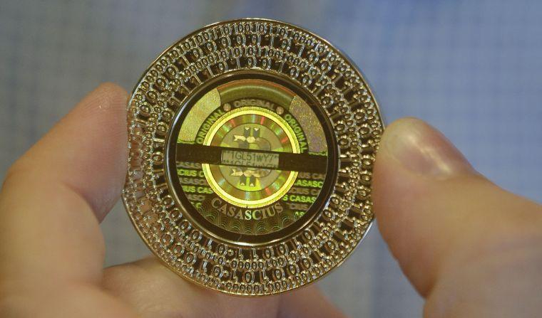 In this April 3, 2013 photo, Mike Caldwell, a 35-year-old software engineer, holds a 25 Bitcoin token at his shop in Sandy, Utah. Caldwell mints physical versions of bitcoins, cranking out homemade tokens with codes protected by tamper-proof holographic seals, a retro-futuristic kind of prepaid cash. With up to 70,000 transactions each day over the past month, bitcoins have been propelled from the world of Internet oddities to the cusp of mainstream use, a remarkable breakthrough for a currency which made its online debut only four years ago. (AP Photo/Rick Bowmer)