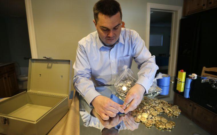 In this April 3, 2013 photo, Mike Caldwell, a 35-year-old software engineer, looks over bitcoin tokens at his shop in Sandy, Utah. Caldwell mints physical versions of bitcoins, cranking out homemade tokens with codes protected by tamper-proof holographic seals, a retro-futuristic kind of prepaid cash. With up to 70,000 transactions each day over the past month, bitcoins have been propelled from the world of Internet oddities to the cusp of mainstream use, a remarkable breakthrough for a currency which made its online debut only four years ago. (AP Photo/Rick Bowmer)
 