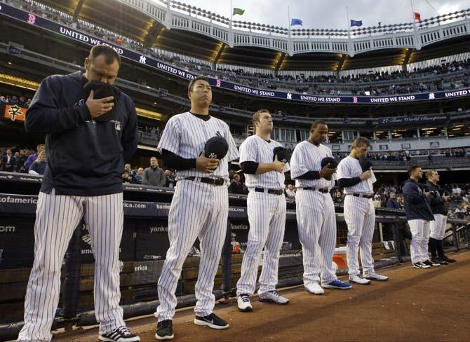 From left, New York Yankees relief pitcher Joba Chamberlain, starting pitchers Hiroki Kuroda, Phil Hughes, CC Sabathia and Andy Pettitte bow their heads during a moment of silence in honor of victims of the Boston Marathon explosions before a baseball game against the Arizona Diamondbacks at Yankee Stadium in New York, Tuesday, April 16, 2013. In big ways and small, New York is putting aside its heated and historical rivalry with Boston in a show of support after the Boston Marathon explosions. (AP Photo/Kathy Willens)
 