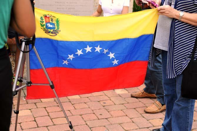 Protesters hold a Venezuelan flag near the Memorial Tower, Tuesday, April 16, 2013. On the current political situation in her home country, native Elsy Carlton Herrera said: "It's hard not being over there, so we're doing everything we can here."
 