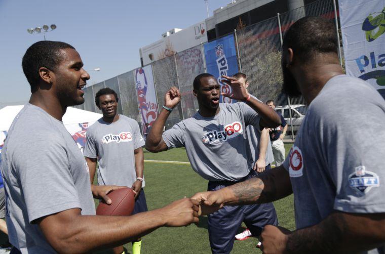 NFL draft prospect Barkevious Mingo of LSU, second from right, jokes with other prospects including E.J. Manuel of Florida State, left, and Ezekiel Ansah of Brigham Young, second from left, during a youth football clinic in New York, Wednesday, April 24, 2013. Many of the top 2013 NFL draft picks are in town for the NFL draft at Radio City Music Hall that starts Thursday. (AP Photo/Seth Wenig)
 