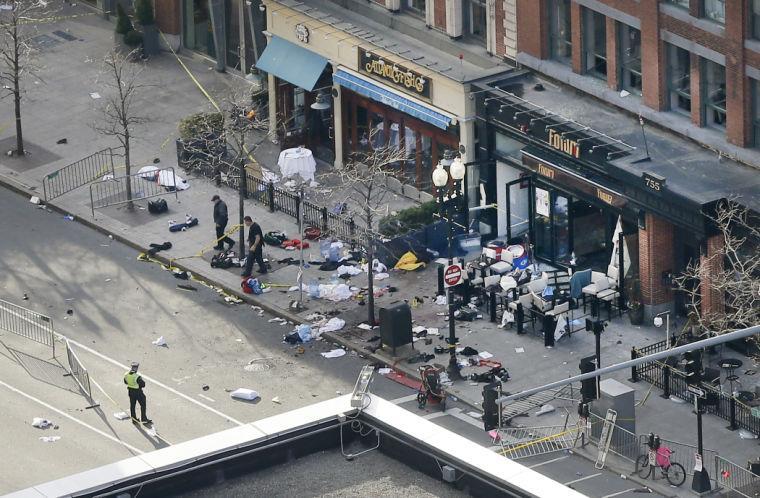 One of the blast sites on Boylston Street near the finish line of the 2013 Boston Marathon is investigated and guarded by police in the wake of two blasts in Boston Monday, April 15, 2013. (AP Photo/Elise Amendola)
 