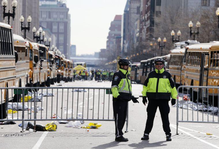 Boston police officers stand on Boylston Street near empty buses meant to transport runners who were instead diverted from the course following an explosion at the finish line, Monday, April 15, 2013, in Boston. (AP Photo/Michael Dwyer)
 