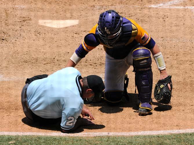 LSU junior catcher Ty Ross (26) checks on home plate umpire Danny Everett May 18, 2013 after a foul ball hit Everett's mask for the second time in the Tigers' 9-11 loss to Ole Miss in Alex Box Stadium. Everett fell to the ground after the ball hit his mask and left the game.
 