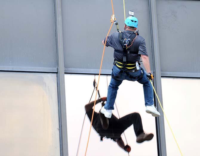 LSU coach Les Miles pushes away from the face of the Capitol One building Thursday, May 30, 2013 during his rappel down the 24 story structure in downtown Baton Rouge. Miles' descent was in effort to raise awareness for Louisiana children available for adoption.
 