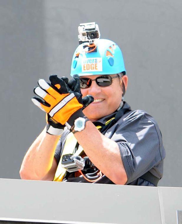 LSU coach Les Miles does his iconic hand-clap in triumph at the base of the Capitol One building Thursday, May 30, 2013 after his rappel down the 24 story structure in downtown Baton Rouge. Miles' descent is in effort to raise awareness for Louisiana children available for adoption.
 