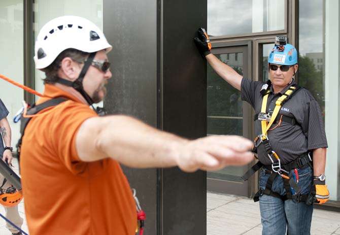 LSU coach Les Miles receives preliminary rappelling instruction at the base of the Capitol One building Thursday, May 30, 2013 before his rappel down the 24 story structure in downtown Baton Rouge. Miles' descent is in effort to raise awareness for Louisiana children available for adoption.
 