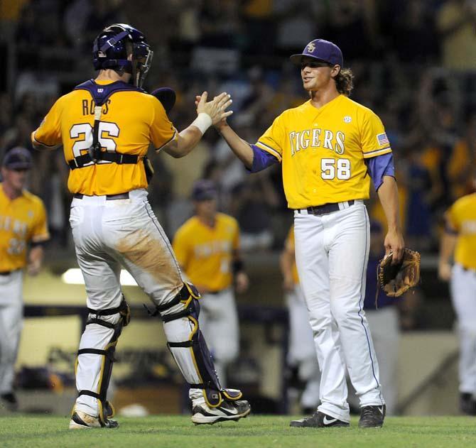 LSU junior catcher Ty Ross (26) high-fives senior closer Chris Cotton (58) following the Tigers' 5-1 win against ULL in Alex Box Stadium.
 