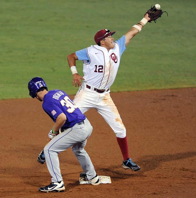 Oklahoma junior infielder Hector Lorenzana (12) stretches to catch a ball while LSU freshman infielder Alex Bregman (30) retreats to second base June 8, 2013 during the Tigers' 11-1 win against Oklahoma in Alex Box Stadium.
 