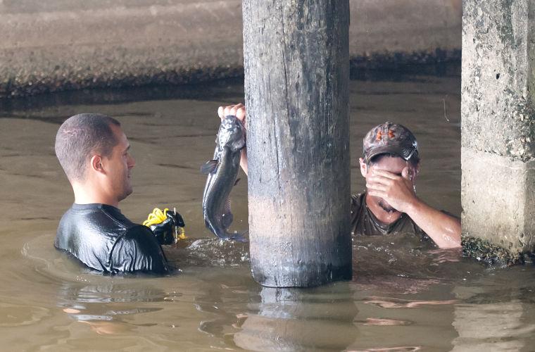 Kyle Ensminger, 19, holds out a catfish to Jason Manwarren, 30, during a fishing trip in University Lake on June 8.
 