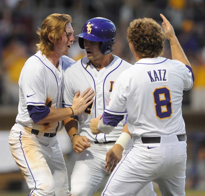 LSU seniors Raph Rhymes (4) and Mason Katz (8) celebrate with sophomore Tyler Moore (2) following Moore's game-winning RBI in the eighth inning of the Tigers' 2-0 win against Oklahoma on June 7, 2013 in Alex Box Stadium.
 