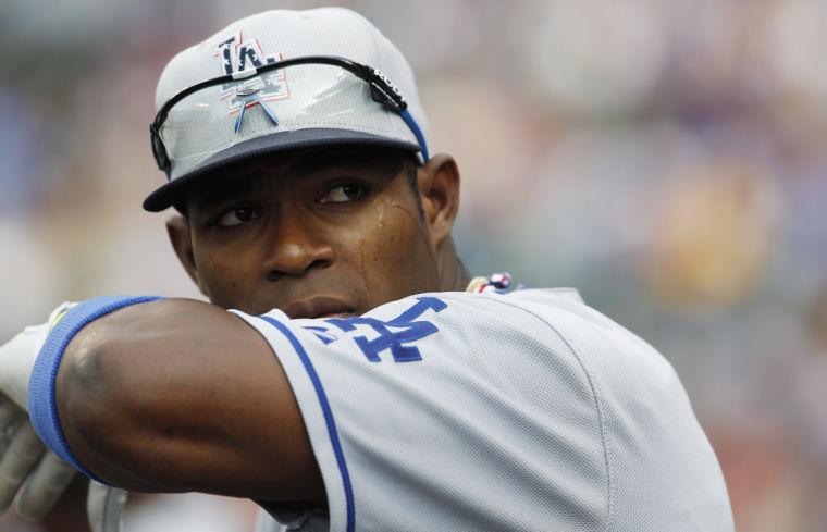 Los Angeles Dodgers right fielder Yasiel Puig hangs over the dugout rail in the first inning of a baseball game against the Colorado Rockies in Denver, Thursday, July 4, 2013.