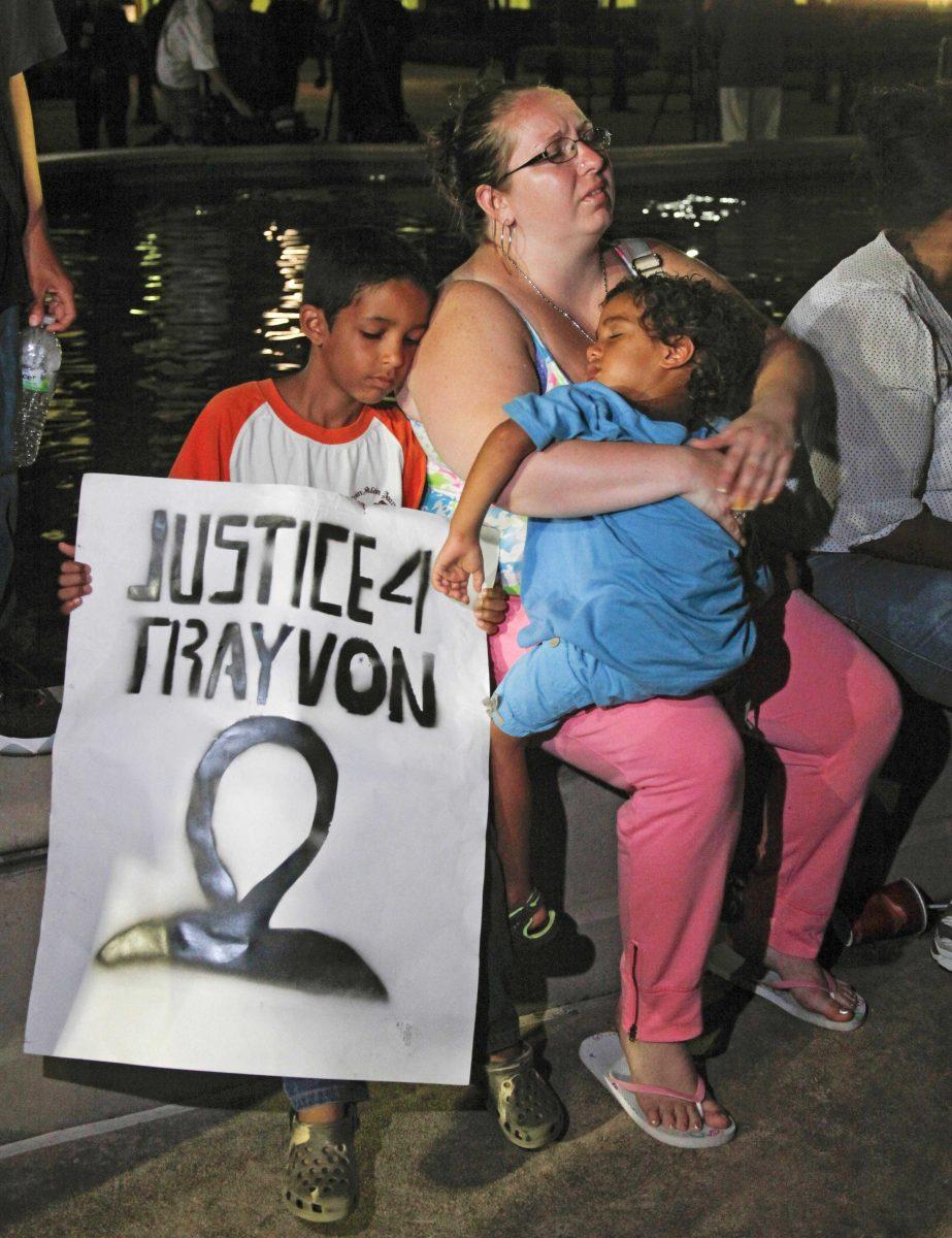 FILE - In this Saturday, July 13, 2013 file photo, a mother holds and sits with her children after hearing the verdict of not guilty in the trial of neighborhood watch volunteer George Zimmerman at the Seminole County Courthouse, in Sanford, Fla. Zimmerman was cleared of all charges Saturday in the shooting of unarmed teenager Trayvon Martin, whose killing unleashed furious debate across the U.S. over racial profiling, self-defense and equal justice. Some view Zimmerman's acquittal as a blow to race relations. (AP Photo/Mike Brown, File)