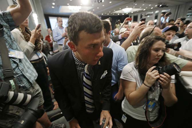 Texas A&amp;M quarterback Johnny Manziel fights his way through a crowd of photographers and reporters as he arrives for the Southeastern Conference football Media Days in Hoover, Ala., Wednesday, July 17, 2013. (AP Photo/Dave Martin)