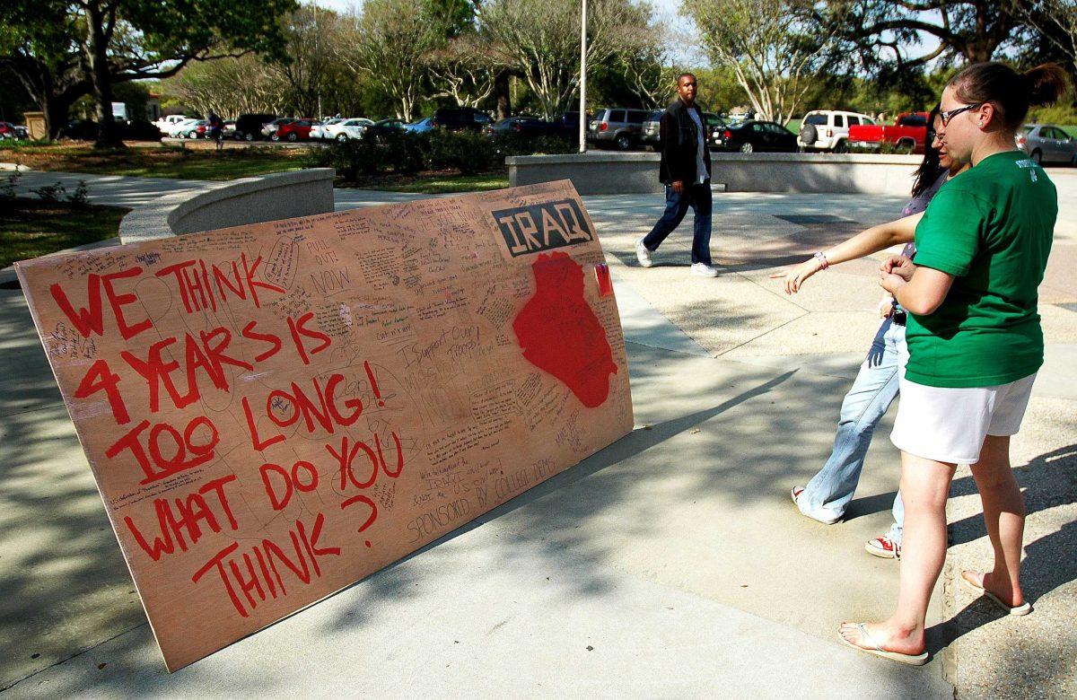 Kayla Frederic, biological sciences freshman (front), and Lesley Brumfield, mass communications freshman (back), look at a sign sponsored by LSU College Democrats in Free Speech Plaza on Monday afternoon. Photo by John Sims