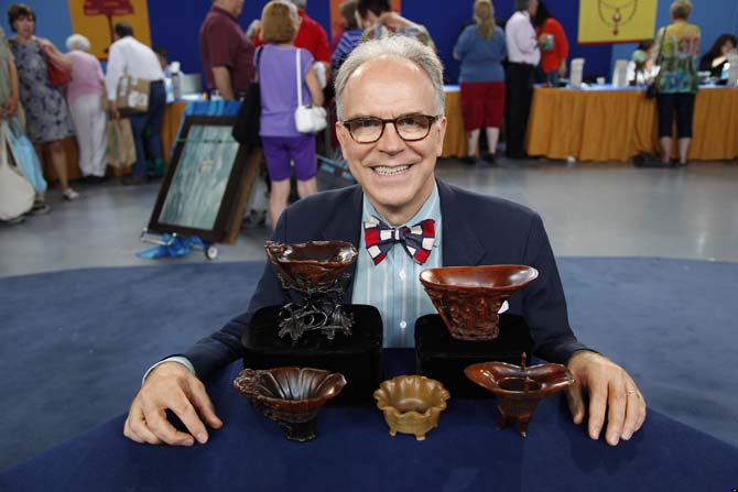 In this Saturday, July 23, 2011 photo, Asian art expert and veteran "Antiques Roadshow." appraiser Lark Mason poses with a collection of Chinese rhinoceros horned cups in Tulsa, Okla. PBS says the collection was judged by Mason to be worth $1 million to $1.5 million, the most valuable item brought in for appraisal in the history of "Antiques Roadshow," which will air its 16th season next year. (AP Photo/WGBH)