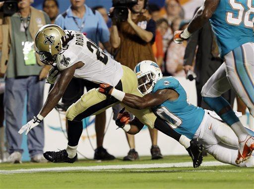 Miami Dolphins defensive back Keelan Johnson (40) tackles New Orleans Saints running back Khiry Robinson (29) during the second half of an NFL preseason football game, Thursday, Aug. 29, 2013, in Miami Gardens, Fla. (AP Photo/Wilfredo Lee)