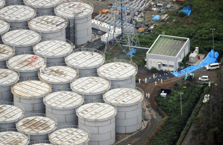 In this Tuesday, Aug. 20, 2013 aerial photo, workers stand on storage tanks at the Fukushima Dai-ichi nuclear plant at Okuma in Fukushima prefecture, northern Japan. Deep beneath Fukushima&#8217;s crippled nuclear power station a vast underground reservoir of highly contaminated water that began spilling from the plant&#8217;s reactors during the 2011 earthquake and tsunami has been creeping slowly toward the sea. (AP Photo/Kyodo News) JAPAN OUT, MANDATORY CREDIT