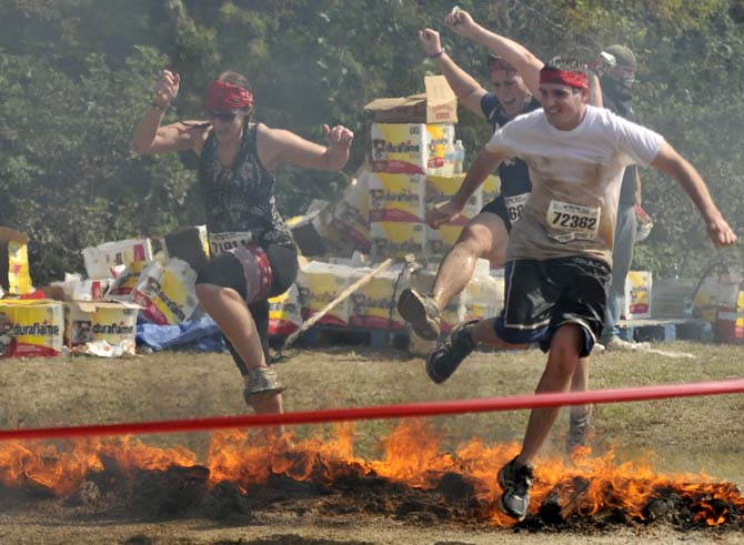 Warrior Dash participants leap over fire October 13, 2012, toward the end of the race in Denham Springs.