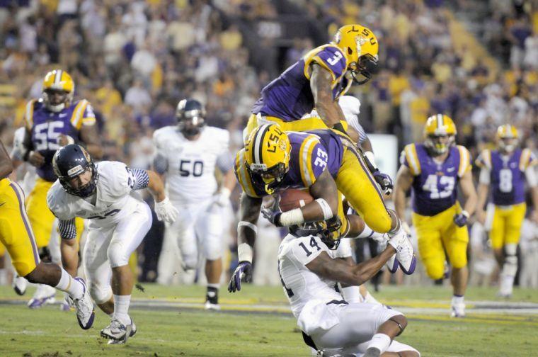 LSU sophomore running back Jeremy Hill (33) leaps over Kent State sophomore Anthony Melchiori on Saturday night, Sept. 14, 2013, in the Tigers' 45-13 victory against Kent State.