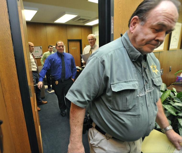 An East Baton Rouge Parish sheriff's deputy, right. and an LSU Police Officer, center of doorway, leave after serving the Louisiana State University Board of Supervisors with legal papers Tuesday, Sept. 10, 2013 in Baton Rouge, La. Standing in the office, from left, are James Marchand, assistant to the General Counsel; Ernie Ballard, LSU PR; and Robert Rasmussen, Assistant Vice President of System Relations, holds the papers. Deputies left empty-handed after trying to get information about LSU's search for a new president from university officials as part of a court order. (AP Photo/The Baton Rouge Advocate, Bill Feig) MAGS OUT; INTERNET OUT; NO SALES; TV OUT; NO FORNS; LOUISIANA BUSINESS INC. OUT (INCLUDING GREATER BATON ROUGE BUSINESS REPORT, 225, 10/12, INREGISTER, LBI CUSTOM); MANDATORY CREDIT