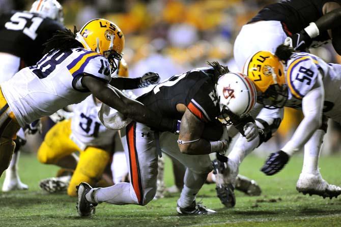 LSU senior linebackers Lamin Barrow (18) and Tahj Jones (58) collaboratively tackle Auburn junior running back Tre Mason (21) Saturday, Sept. 21, 2013 during the Tigers' 35-21 victory against Auburn in Tiger Stadium.