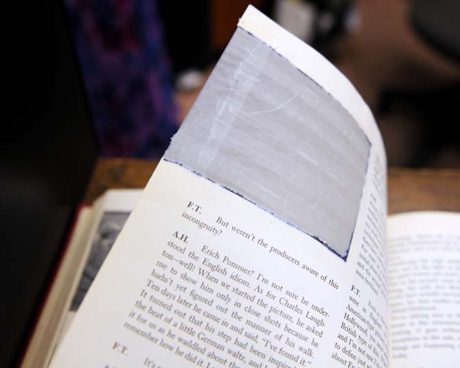 A damaged library book with a photo cut out of it rests on a shelf Wednesday, September 25, 2013, in Middleton Library. A new campaign is being launched to prevent students from damaging books.