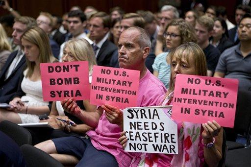 CODEPINK co-founder Medea Benjamin, right, and other protestors hold up signs in the hearing room on Capitol Hill in Washington, Tuesday, Sept. 3, 2013, as Secretary of State John Kerry and Defense Secretary Chuck Hagel testified before the Senate Foreign Relations Committee to advance President Barack Obama's request for congressional authorization for military intervention in Syria, a response to last month's alleged sarin gas attack in the Syrian civil war. (AP Photo/J. Scott Applewhite)