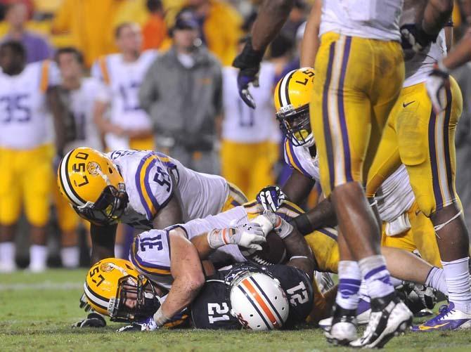 LSU junior linebacker D.J. Welter (31) and senior defensive end Jermauria Rasco (59) tackle an Auburn player Saturday, September 21, 2013, during the Tigers' 35-21 victory against Auburn in Tiger Stadium.