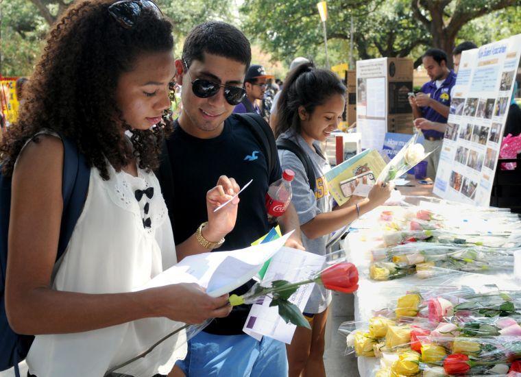 Students Maria Paula Gomez and Gustavo Gonzalez read Quran quotes handed out by the Saudi Club Wednesday, Sept. 11, 2013 at the Student Involvement Fair in Free Speech Alley.