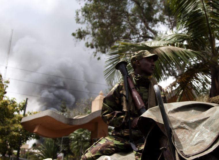 A soldier holds a RPG near the Westgate shopping mall in Nairobi, Kenya, as smoke rises from it, Monday Sept 23 2013. Islamic extremist gunmen lobbed grenades and fired assault rifles inside Nairobi's top mall Saturday, killing dozens and wounding over a hundred in the attack. Multiple large blasts have rocked the mall Monday where a hostage siege is in its third day. Associated Press reporters on the scene heard multiple blasts and a barrage of gunfire. Security forces have been attempting to rescue an unknown number of hostages inside the mall held by al-Qaida-linked terrorists. (AP Photo/ Sayyid Azim)