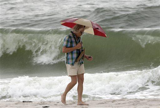 Sandra Samford of Crane Hill, Ala., collects shells as she walks along the beach during a squall in Gulf Shores, Ala., Sunday, Oct. 6, 2013. Forecasters said that Tropical Storm Karen dissipated late Sunday morning as storm preparations in the region were called off or scaled back. (AP Photo/Dave Martin)