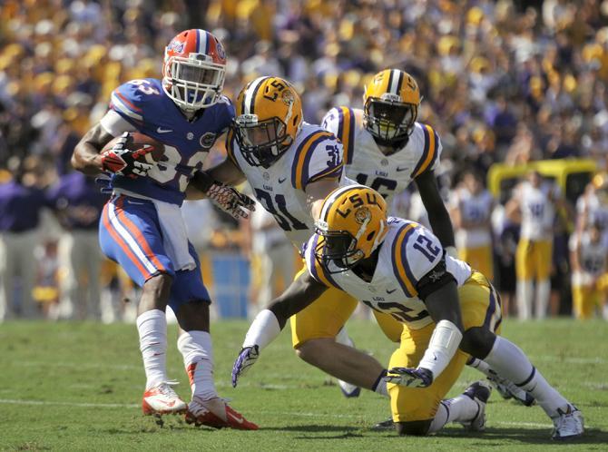 LSU junior linebacker D.J. Welter (31) and sophomore safety Corey Thompson (12) attempt to tackle Florida senior wide receiver Solomon Patton (83) on Saturday, Oct. 12, 2013 during the Tigers' 17-6 victory against the Gators in Tiger Stadium.