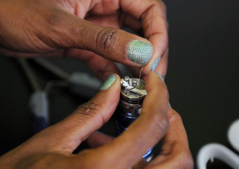 Novelle Gibson secures a wick in the atomizer of an electronic cigarette.