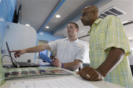 David Smith, center, with Independence Blue Cross (IBC) discuses the opening health insurance exchange and provides information on health car reform to George Allen Tuesday, Oct. 1, 2013, at IBC's mobile education and enrollment center in Philadelphia. Tuesday is the first day of the open enrollment period for new health insurance options under the 2010 federal health care law. (AP Photo/Matt Rourke)