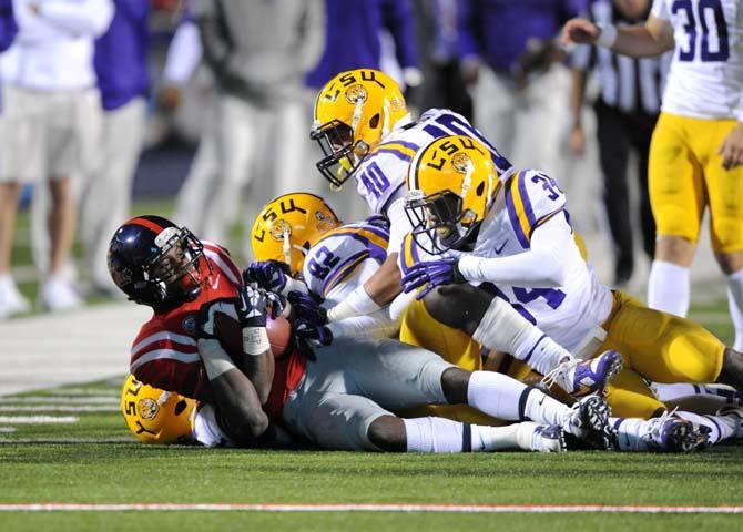 LSU senior wide receiver James Wright (82), sophomore linebacker Duke Riley (40) and sophomore safety Micah Eugene (34) tackle an Ole Miss offensive player Saturday, October 19, 2013 during the Tigers' 27-24 loss against the Rebels at Vaught-Hemingway Stadium.